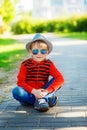 Fashionable little boy in sunglasses and cap sitting on acphalt Royalty Free Stock Photo