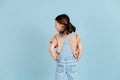 Fashionable little girl posing with her back turned over blue background