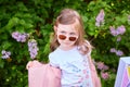 fashionable little girl in sunglasses walks through a blooming garden. Royalty Free Stock Photo