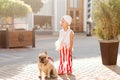 Fashionable little girl walks with a dog - a French bulldog in the city Royalty Free Stock Photo