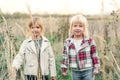 Fashionable little girls at nature. Adorable little sisters on walk at countryside. Girlfriends enjoying nature at field. Happy