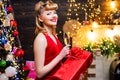 Fashionable luxury girl celebrating new year. Retro woman near the Christmas tree. Smiling woman in evening red dress