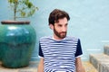 Fashionable male model in striped shirt sitting outdoors