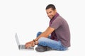 Fashionable man sitting on floor using laptop smiling at camera Royalty Free Stock Photo