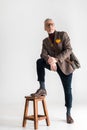 Fashionable mature man putting leg on chair while standing Royalty Free Stock Photo