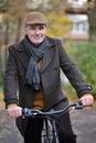 Fashionable mature man wearing woolen coat and hat standing with bicycle