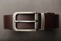 Fashionable men`s brown belt made of genuine leather with a light metal buckle on a dark background. Genuine leather, handmade Royalty Free Stock Photo