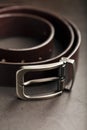 Fashionable men`s brown belt made of genuine leather with a light metal buckle on a dark background. Genuine leather, handmade Royalty Free Stock Photo