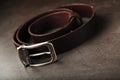 Fashionable men`s brown belt made of genuine leather with a light metal buckle on a dark background. Genuine leather, handmade Royalty Free Stock Photo