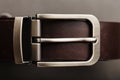 Fashionable men`s brown belt made of genuine leather with a light metal buckle on a dark background. Genuine leather, handmade Royalty Free Stock Photo