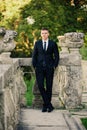 Fashionable model groom standing on the balcony leaning on railing