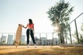 Fashionable model posing with longboard on playground on sunset background. Street stylish photo of girl in casual clothes Royalty Free Stock Photo