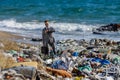 Businessman looking at watch, checking time standing on pile of waste on beach. Consumerism versus pollution concept Royalty Free Stock Photo