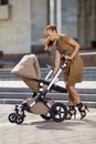 Fashionable modern mother on a urban street with a pram. Young m