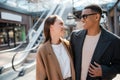 fashionable multiethnic couple in coats smiling