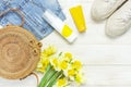 Fashionable natural organic round rattan bag, denim shorts, beige women`s espadrilles, sunscreen, yellow narcissus daffodil
