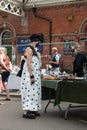 Fashionable older woman in face mask browsing vendor stalls at outdoor antique flea market