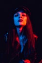 Fashionable portrait of a stylish girl in a leather jacket and cap with a neon light