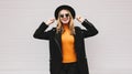 Fashionable portrait stylish happy smiling young woman having fun female model posing wearing a black coat, round hat on city Royalty Free Stock Photo