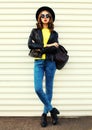 Fashionable portrait stylish young woman model posing wearing a black rock style jacket, yellow sweater, backpack on white Royalty Free Stock Photo