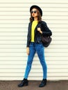 Fashionable portrait stylish young woman model posing wearing a black rock style jacket, yellow sweater, backpack on white Royalty Free Stock Photo