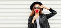Fashionable portrait stylish young woman with red heart shaped lollipop blowing her lips sending sweet air kiss wearing a black Royalty Free Stock Photo