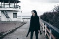 Fashionable portrait of a young brunette woman in black clothes, jeans T-shirt, coat and sunglasses, in a Gothic style sad mood Royalty Free Stock Photo