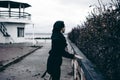 Fashionable portrait of a young brunette woman in black clothes, jeans T-shirt, coat and sunglasses, in a Gothic style sad mood Royalty Free Stock Photo