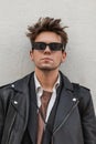 Fashionable portrait young man with serious face in a vintage dark sunglasses in a trendy leather black jacket with a stylish Royalty Free Stock Photo