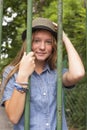 Fashionable pretty girl in the park behind the fence. Travel. Royalty Free Stock Photo