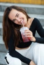 Fashionable pretty stylish girl smiling and drinking cold lemonade. Street fashion. Beautiful young brunette woman wearing white Royalty Free Stock Photo