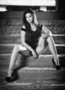 Fashionable pretty young woman with long legs sitting on old stone stairs. Beautiful long hair brunette on high heels shoes posing Royalty Free Stock Photo