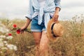 Fashionable of rustic summer female accessory and clothes. Woman holding straw hat wearing linen shirt in meadow Royalty Free Stock Photo