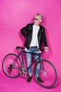 Fashionable senior man wearing leather jacket and sunglesses standing with bicycle Royalty Free Stock Photo