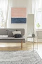 Fashionable settee with pillows in bright living room interior with pastel pink and blue painting