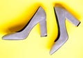 Fashionable shoes concept. Shoes made out of grey suede on yellow background. Pair of fashionable high heeled shoes