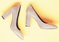 Fashionable shoes concept. Shoes made out of grey suede on yellow background. Pair of fashionable high heeled shoes