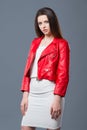 Fashionable style, fashion women`s clothing, color combination. Beautiful brunette girl in white dress and red leather jacket