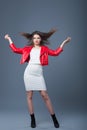 Fashionable style, fashion women`s clothing, color combination. Beautiful brunette girl in white dress and red leather jacket.