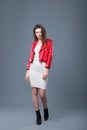 Fashionable style, fashion women`s clothing, color combination. Beautiful brunette girl in white dress and red leather jacket