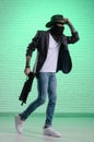 fashionable stylish man in a jacket and a cowboy hat in a balaclava with a gun