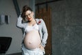 Fashionable stylish young pregnant woman in a gray jacket with denim overalls and a white bra. Royalty Free Stock Photo