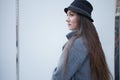 Fashionable stylish young woman with long hair, black hat and gray long coat walks in the city center Royalty Free Stock Photo