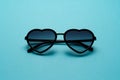 Fashionable sunglasses in shape of heart on blue background. Top view. Flat lay. Minimal style with colorful paper backdrop