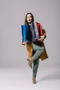 fashionable surprised woman in beige coat holding shopping bags on grey. Royalty Free Stock Photo