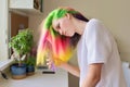 Fashionable teen girl with trendy rainbow dyed hair combing hair at home