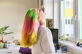 Fashionable teen girl with trendy rainbow dyed hair combing hair at home