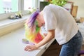 Fashionable teen girl with trendy rainbow dyed hair combing hair at home