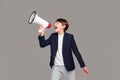 Fashionable teenager boy screaming through megaphone in studio. A lot of copy space Royalty Free Stock Photo