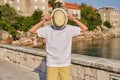 A fashionable teenager boy in a white t-shirt covers his face with a straw hat. Royalty Free Stock Photo